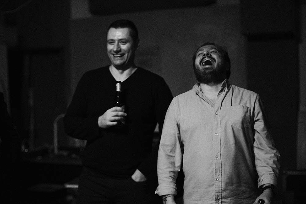 Zdjęcie z afterparty festiwalu Dreszczówka. Pisarze Tomasz Czarny i Patryk Bogusz rozmawiają i się śmieją.